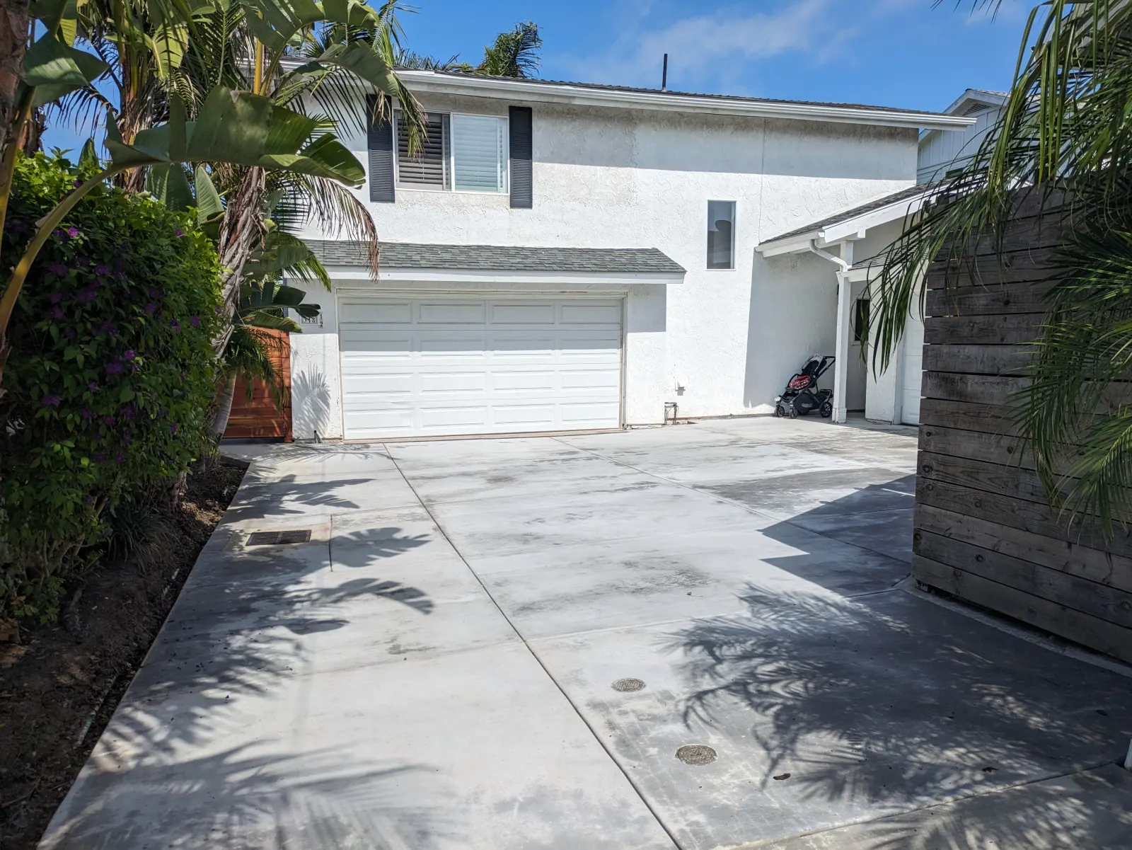 Concrete driveway leading to a two-story white house with a closed white garage door.
