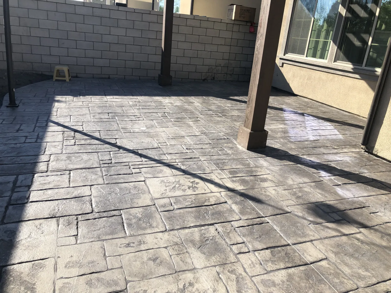 Patio floor with a ashlar stone pattern stamped concrete finish under a shade structure.