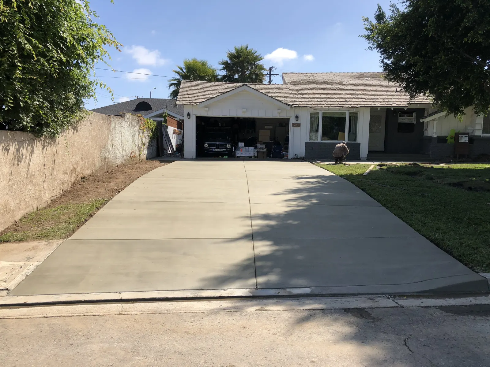 A newly poured concrete driveway leading from the street up to a suburban house garage.