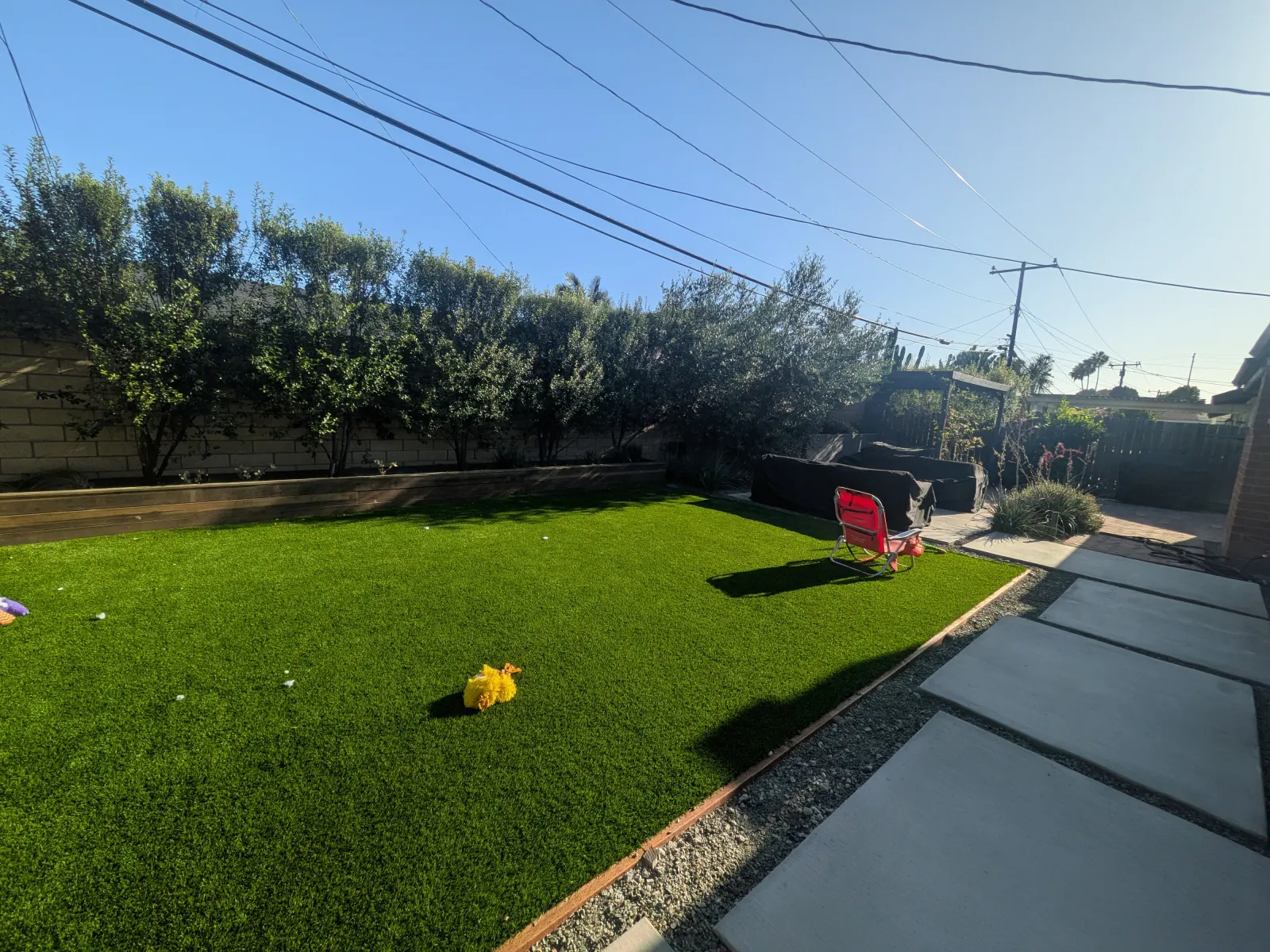 Artificial grass lawn bordered by large concrete stepping stones and gravel.